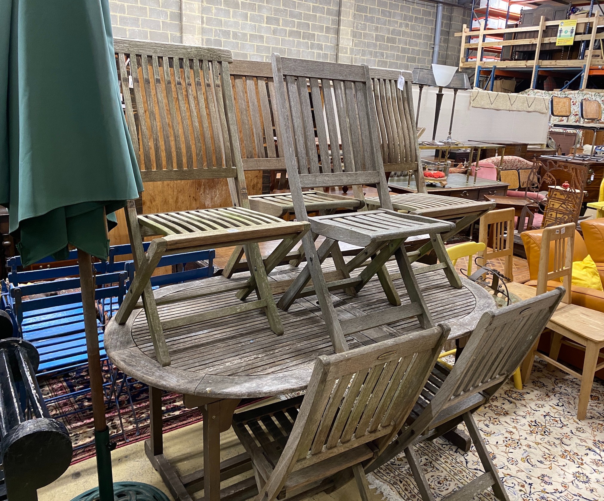 A weathered teak extending garden table, length 170cm, width 100cm, height 74cm parasol with cast metal base and six folding chairs (four and two)